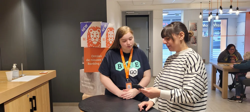 Beego-student helpt een klant met de ING Bank-app in het kantoor
